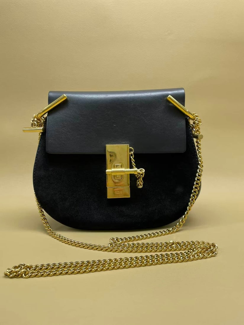 CHLOÉ BLACK CALFSKIN CHAIN SADDLE BAG: CHLOÉ BLACK CALFSKIN CHAIN SADDLE BAG CHLOÉ. A black calfskin saddle bag with a flap closure, metal clasp and chain shoulder strap, designed for shoulder or crossbody carry. Accompanied by a dust