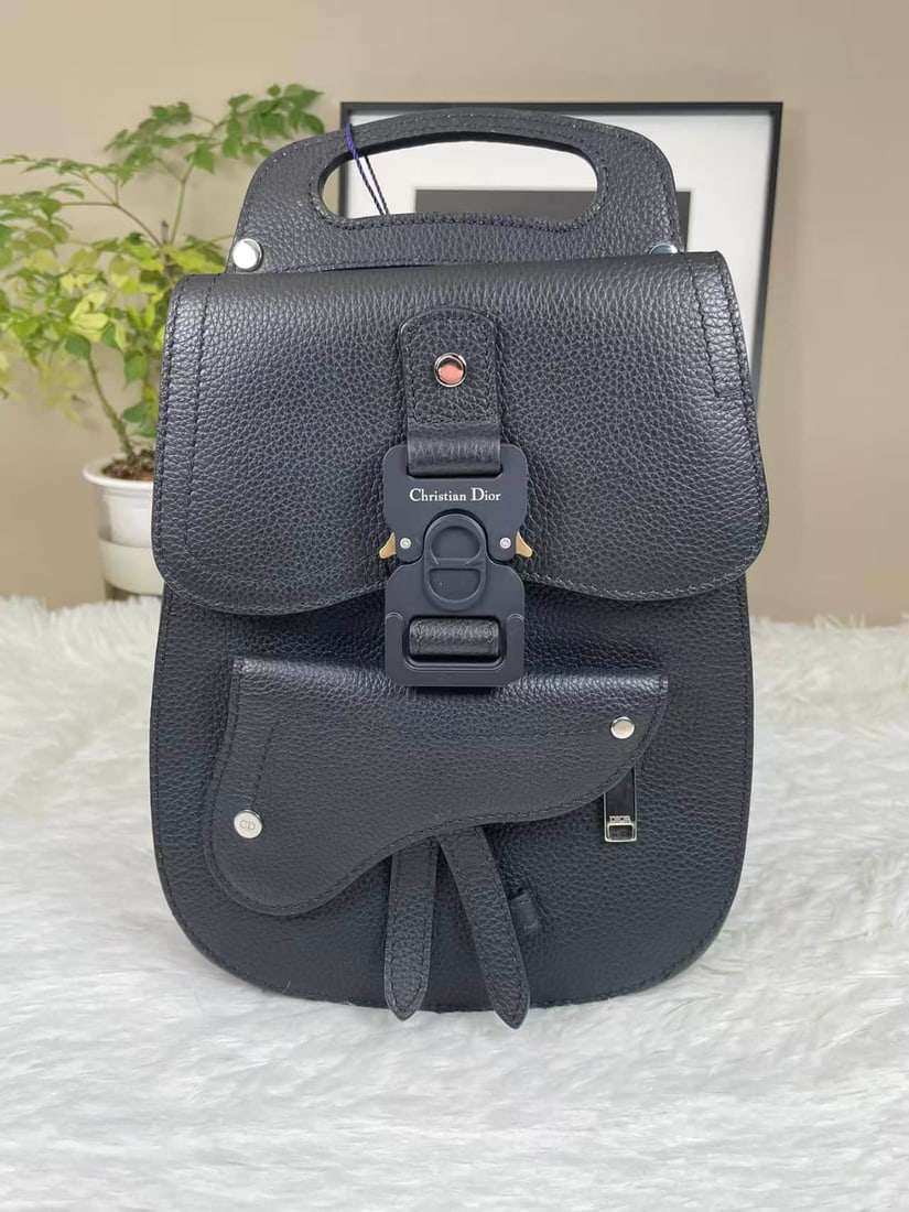 DIOR SADDLE SMALL CALFSKIN BACKPACK: DIOR SADDLE SMALL CALFSKIN BACKPACK DIOR, Saddle Backpack, Small. A black grained calfskin backpack with black-tone metal fittings and mechanical-style buckle closures. Designed for backpack or