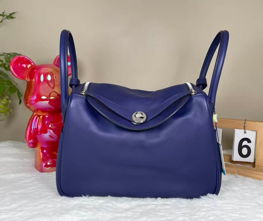 HERMÈS LINDY 30 BICOLOUR SWIFT LEATHER HANDBAG: HERMÈS LINDY 30 BICOLOUR SWIFT LEATHER HANDBAG HERMÈS, Lindy 30. A bicolour Swift leather handbag in Bleu Encre and Bleu Zellige, finished with palladium-plated hardware. Presented in near-unused