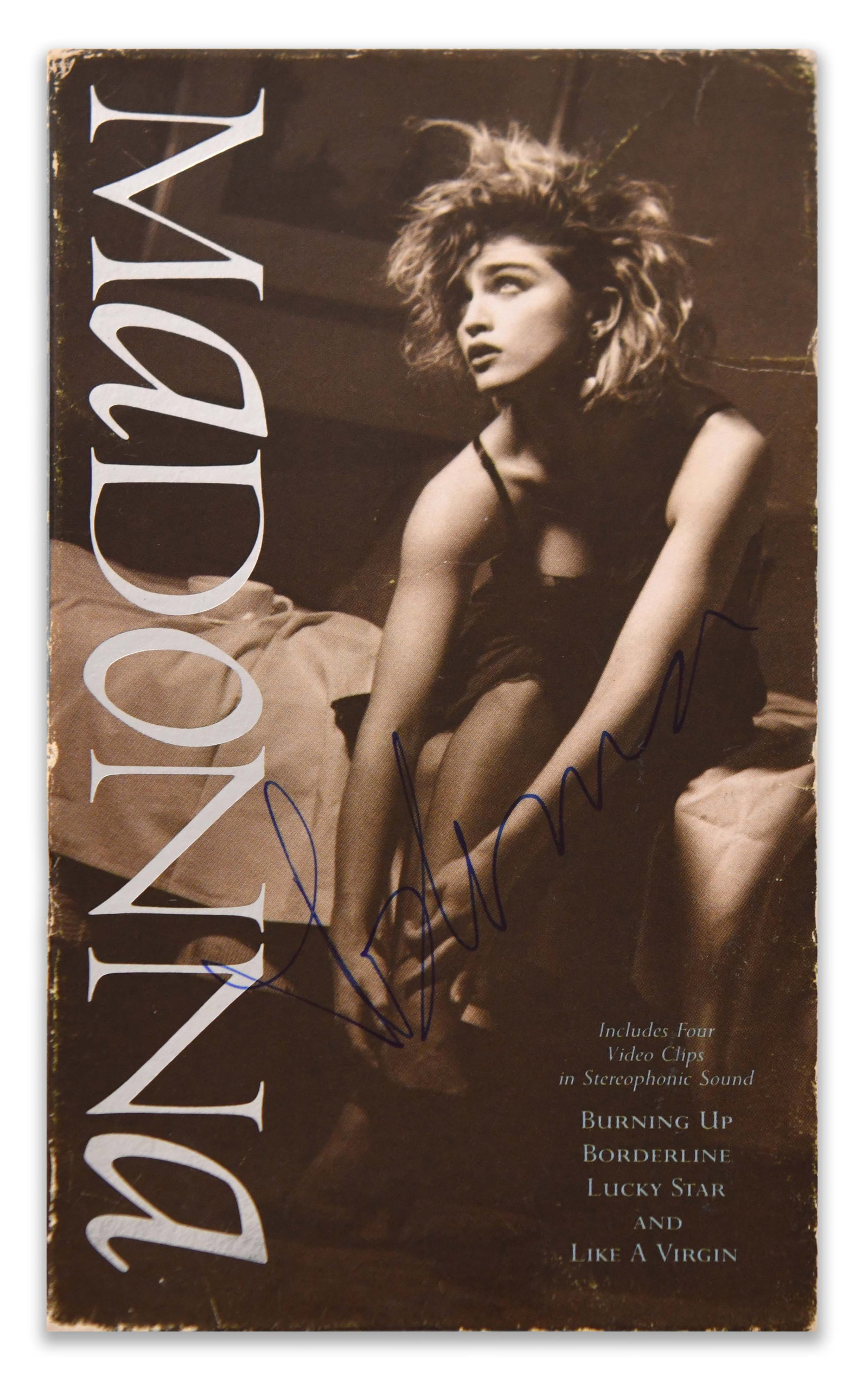 MADONNA, MADONNA VIDEO CASSETTE: MADONNA, MADONNA VIDEO CASSETTE Signature: Madonna Description: A vintage Madonna video cassette featuring an early-career photographic portrait and a selection of four music videos: "Burning Up," "Bo