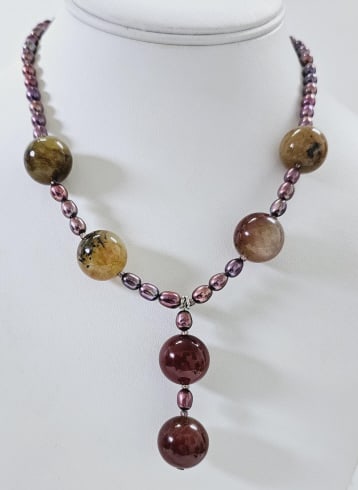 Silver Tone Pearl & Jasper Drop Necklace Necklace measures: Necklace measures 20" This necklace features Jasper beads, showcasing a mix of earthy browns, purples, and tans. The beads are strung on a delicate strand of purple freshwater pearls, creating an eleg