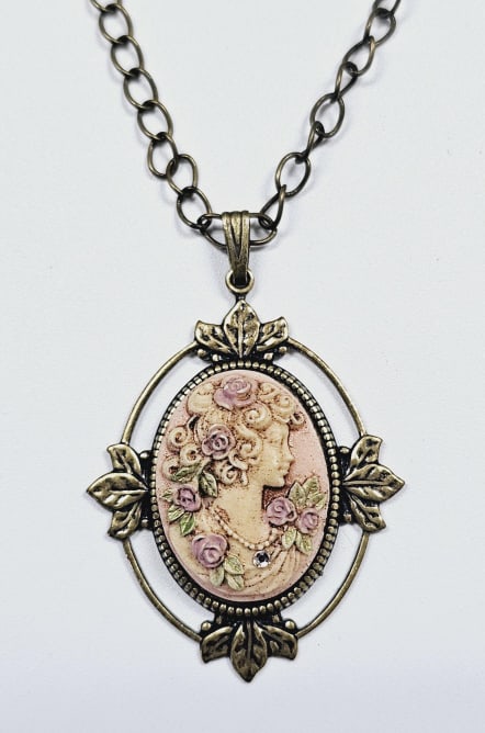 Victorian Style Celluloid Cameo Necklace Necklace measures: Necklace measures 22" This is a vintage necklace with an oval pendant featuring a cameo of a woman in profile, surrounded by roses. The cameo is set in a bronze-colored frame adorned with leaf designs