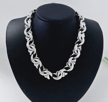 1960s Coro Signed Silver Tone Necklace Necklace measures: Necklace measures 16" This is a chunky silver necklace with a bold, textured design. It appears to be a variation of a Byzantine chain, featuring interlocking oval links that create a substantial and