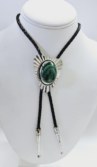 Silver Tone Malachite Bolo Tie Measures: Measures 38" It features a braided black leather cord with silver tone metal tips and a large decorative slide. The slide is silver tone and has a teardrop-shaped malachite stone in the center. The st