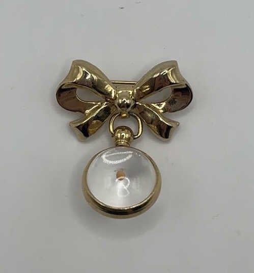 Vintage Cora Mustard Seed Bow Brooch The Vintage Coro Mustard Seed In Lucite Bow Brooch is a yellow: The Vintage Coro Mustard Seed In Lucite Bow Brooch is a yellow gold brooch with a mustard seed and a clear lucite ball. The bow is 1 1/4 inches wide and the brooch is 1 1/2 inches long.