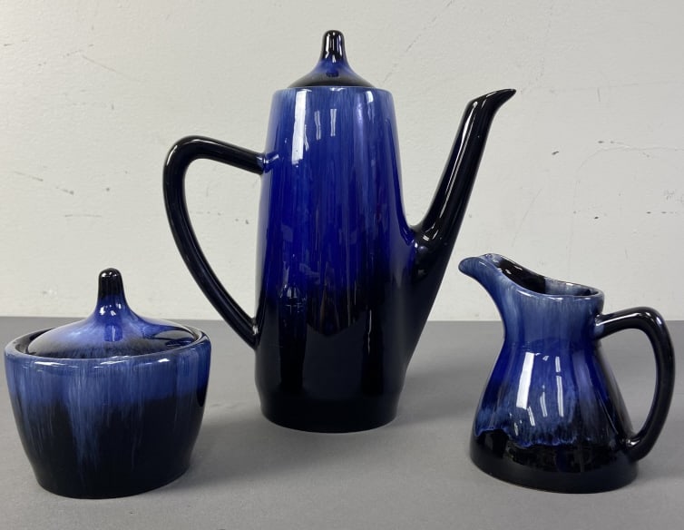 Blue Mountain Pottery Coffee Set of Three Set includes coffee pot, sugar bowl, and creamer in a blue: Set includes coffee pot, sugar bowl, and creamer in a blue and black drip glaze. Clean, no chips or cracks. Sugar bowl and coffee pot include lids. Creamer is 4 1/2 inches tall, creamer is 4 inches ta