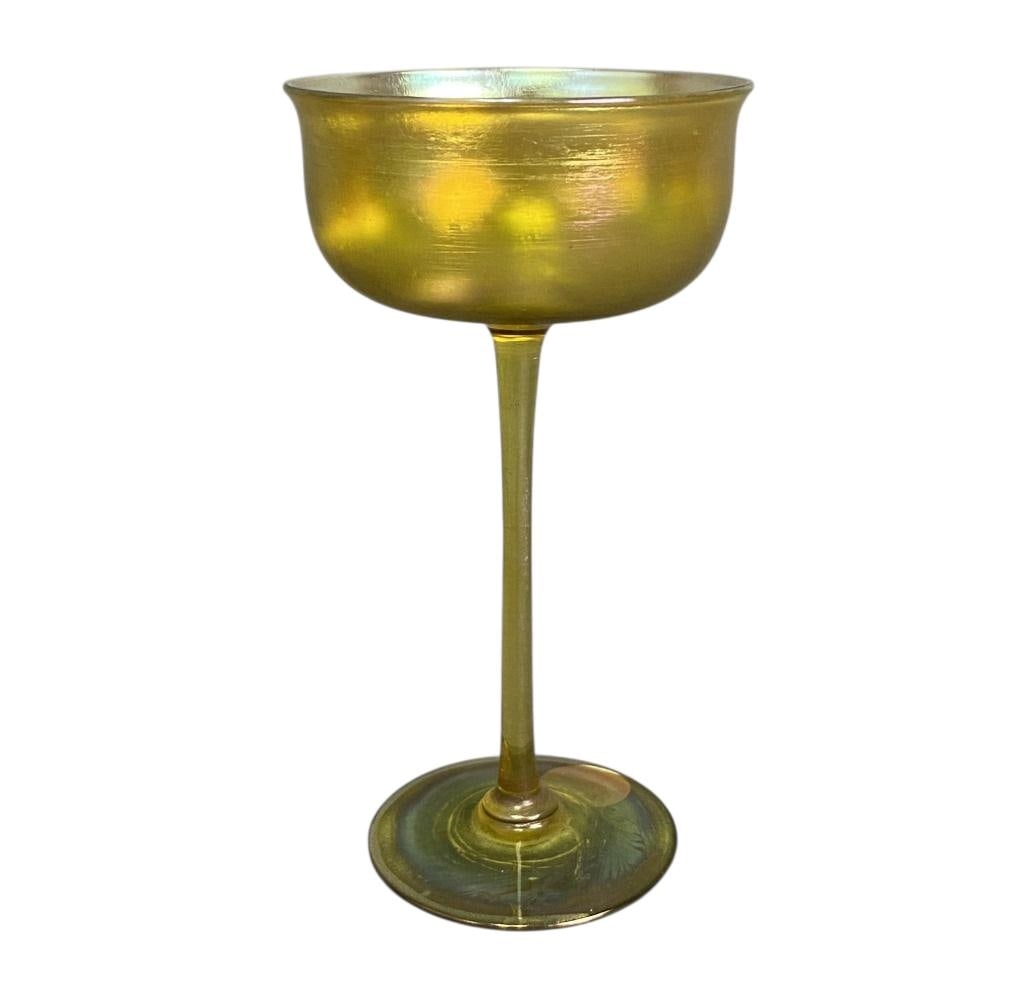 LC Tiffany Favrile Champagne Glass Yellow iridescent favrile glass stemmed champagne glass by Louis: Yellow iridescent favrile glass stemmed champagne glass by Louis Comfort Tiffany. Marked LCT Favrile on the bottom. Clean, no cracks or chips. Glass is 5 3/4 inches tall.