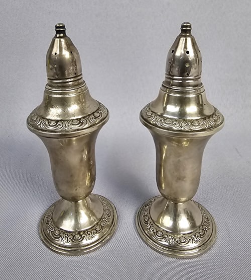 A Pair of A.M.C. Weighted Sterling Silver Shakers Shakers weigh 338 Grams Total: Shakers weigh 338 Grams Total 5.5 inches tall A pair of weighted sterling silver shakers by A.M.C., featuring an ornate classical style with urn-shaped bodies, flared bases, and tapered, perforated to