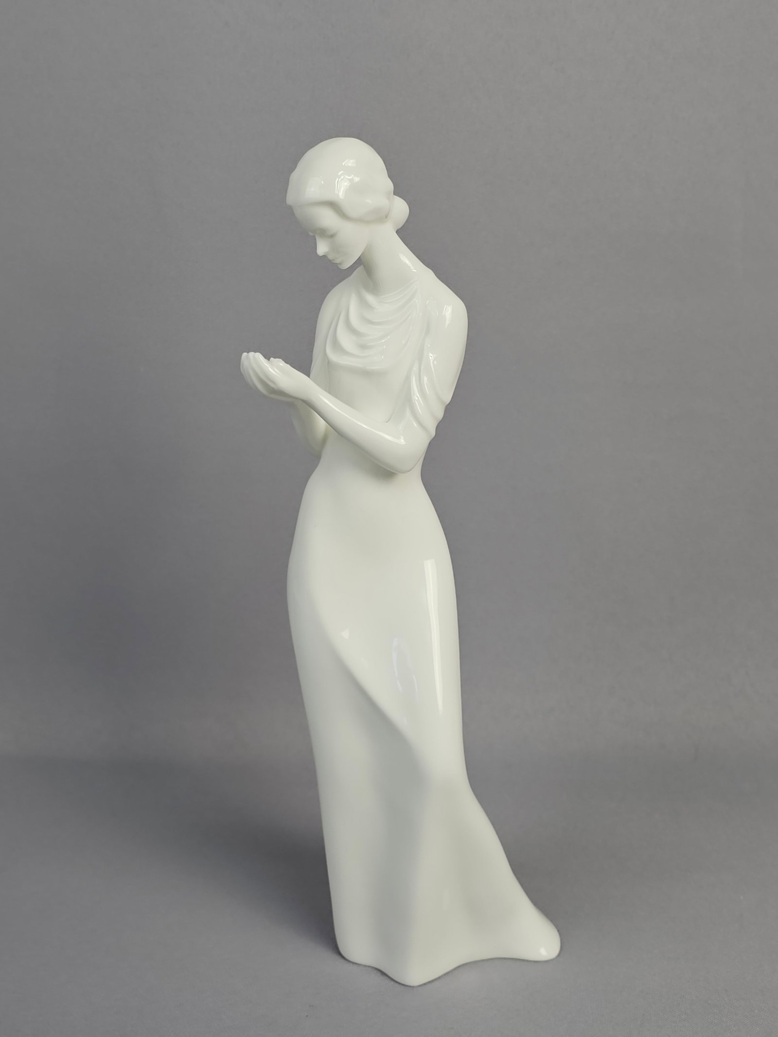 Royal Doulton Bone China Figurine 'Tenderness' HN 2713: A Royal Doulton bone china figurine titled 'Tenderness', model number HN 2713. The white glazed figurine depicts a slender female figure in an elegant style, looking downwards and gently holding a sma
