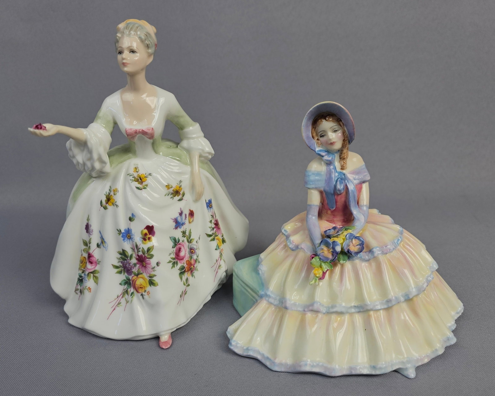 A Pair of Royal Doulton Bone China Figurines: 'Daydreams' HN 1731 and 'Diana' HN 2468: A pair of Royal Doulton bone china figurines, hand-made and hand-decorated in England. The first, titled "DAYDREAMS" (HN 1731, © 1935, modelled by Leslie Harradine), depicts a seated lady in a pastel