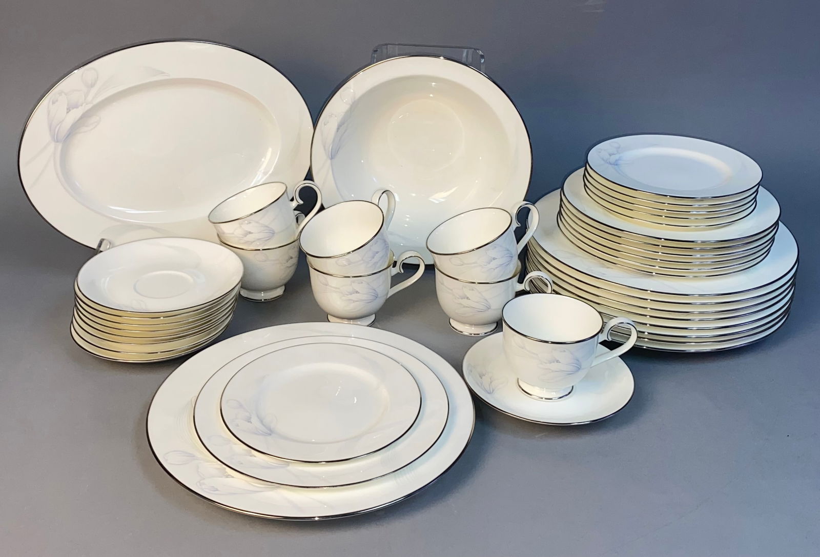 A Large Set of Noritake Bone China 'Wind Blossom' Pattern 4719 Dinnerware: A 40 piece set of Noritake Bone China dinnerware in the "Wind Blossom" pattern, number 4719. Each piece is crafted from white/cream bone china, featuring elegant silver-colored rims and adorned with a