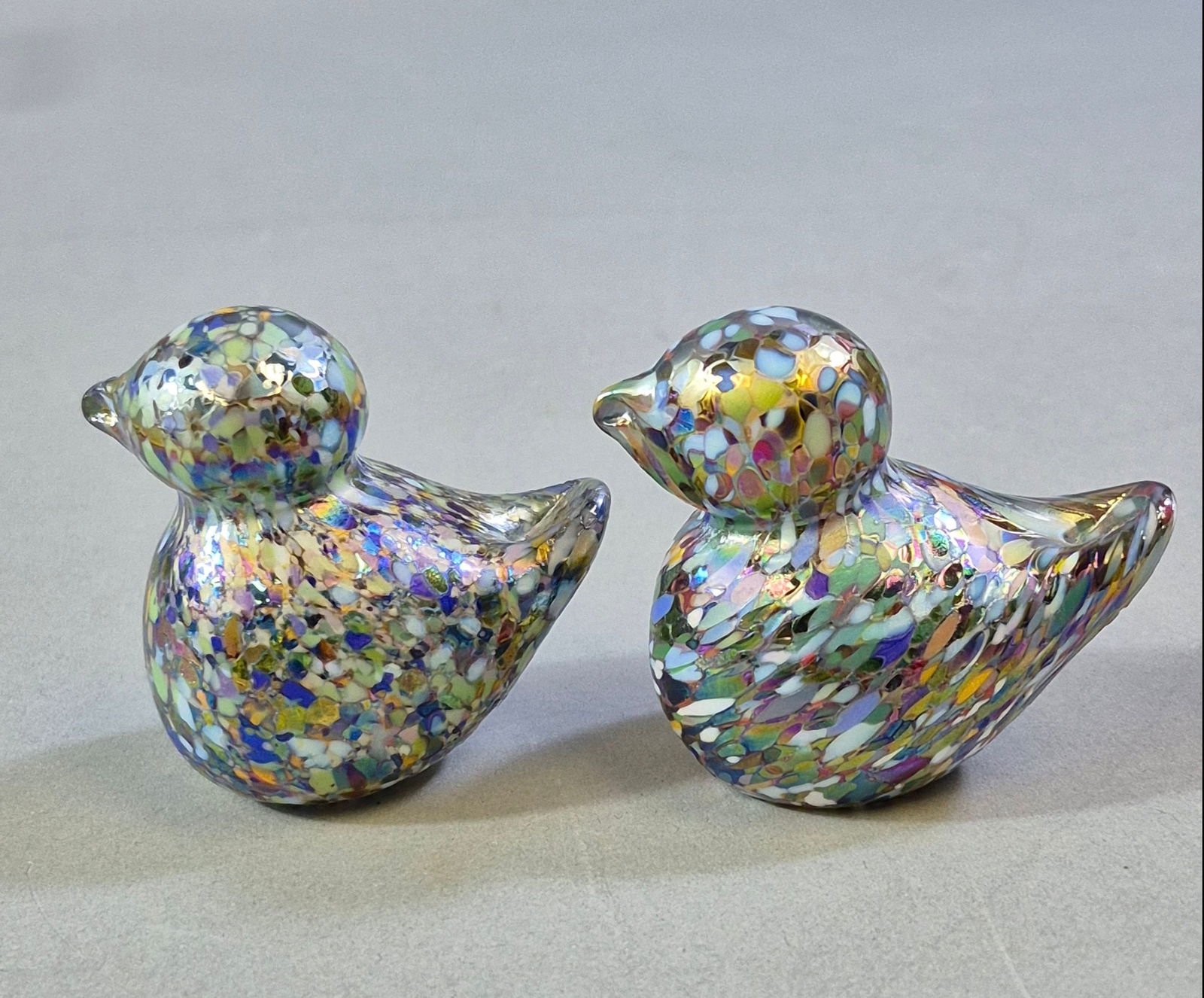 A Pair of R. A. Huddleson (2011) Confetti Art Glass Bird Paperweights: A pair of decorative art glass figurines by R. A. Huddleson, dated 2011. Crafted in a style comparable to Murano confetti glass, each stylized as a bird and featuring an intricate inclusion of numerou