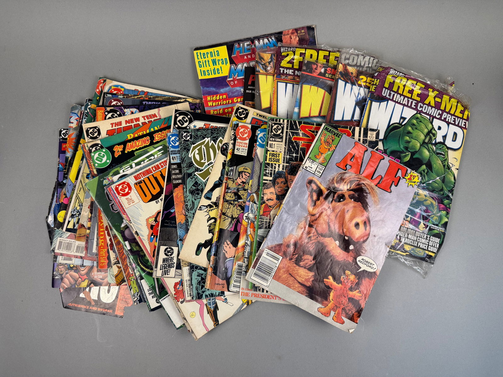 A Collection of Marvel and DC Comic Books and Related Magazines 70s-90s: A collection of American comic books and related magazines, primarily from Marvel and DC Comics, dating from the mid-to-late 1980s. Visible titles include "ALF, " "The New Teen Titans,
