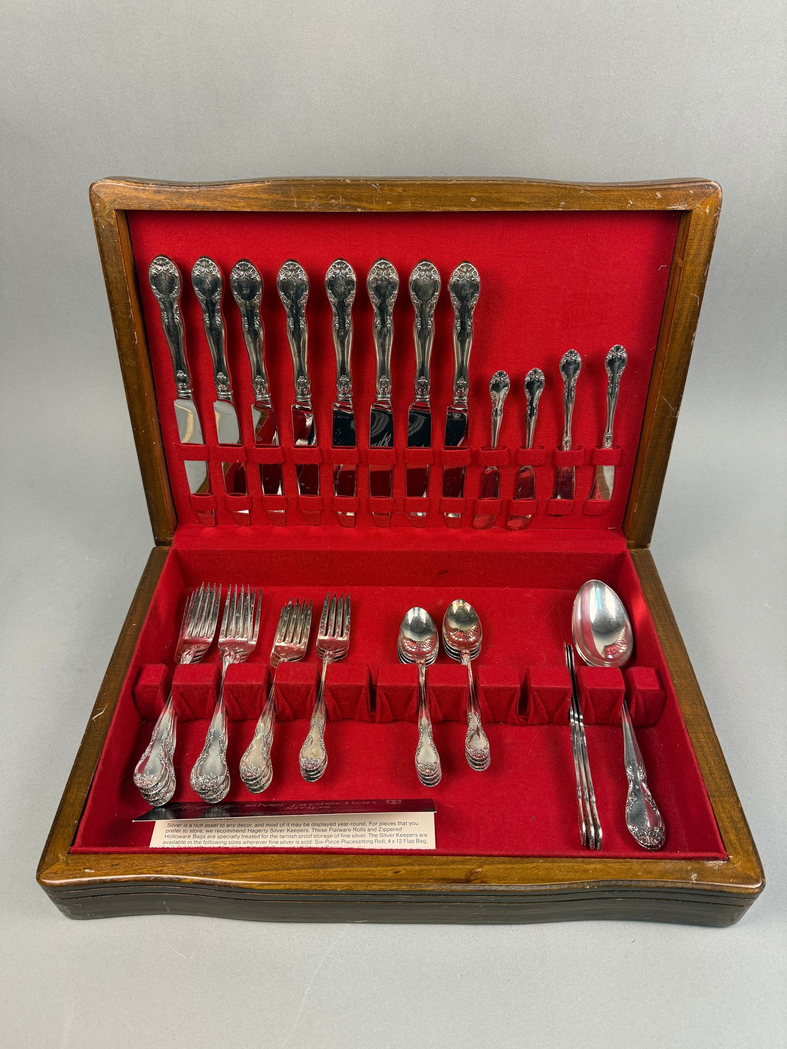 Set of Gorham Plated 'Baronial' Flatware: Gorham plated flatware in the 'Baronial' pattern, presented in a dark brown wooden box with a slightly bowed front and a red velvet-lined interior designed for specific pieces. The set includes eight