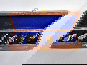 A Set of Six Modern Nautical Brass Miniature Instruments, Made in India: A set of six miniature nautical instruments presented in a rectangular, polished wooden box with a brass-toned clasp and a royal blue velvet-lined interior. The instruments include a compass, a diver'