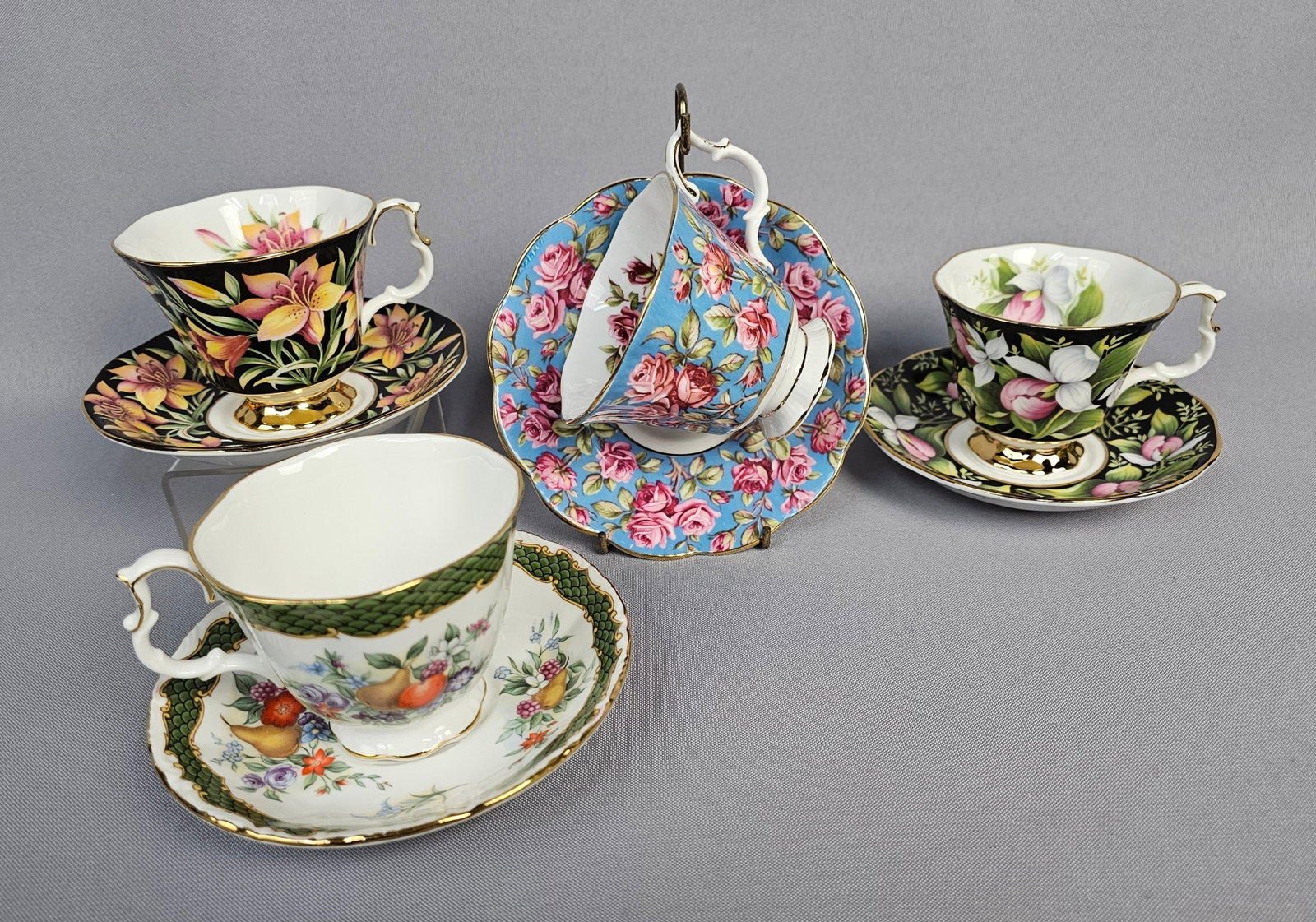 A Collection of Royal Albert Bone China Teacup and Saucer Sets, including 'Harewood' from the Merrie: A collection of four distinct Royal Albert Bone China teacup and saucer sets, primarily in a traditional English style characterized by scalloped edges and gold-gilt trim. The collection includes: * O