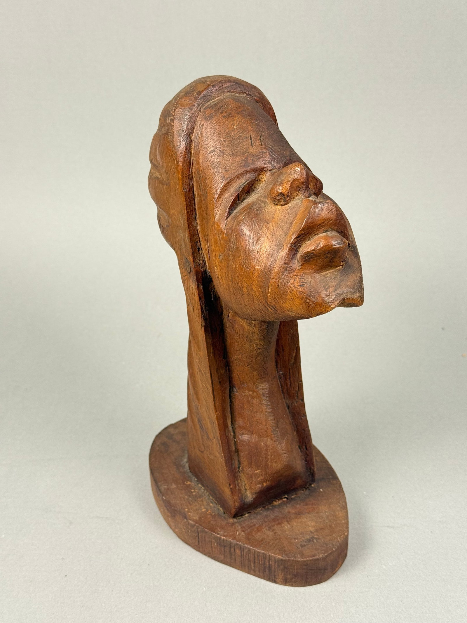 Vintage Hand Carved Wood Head Tribal Sculpture: A vintage Haitian hand-carved wood sculpture by Roger Francois, depicting a stylized human head or bust. The piece is characterized by an elongated form, closed eyes, and prominent lips, presented in 