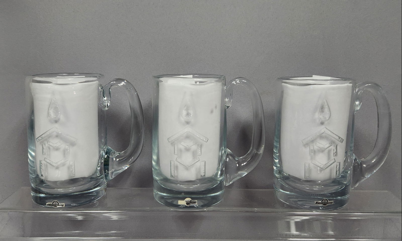 Three Strombergshyttan 1972 Olympic Limited Edition Crystal Tankards: A set of three Strombergshyttan 1972 Olympic Limited Edition Crystal Tankards. Each clear glass tankard features an etched or sandblasted commemorative design depicting a stylized Olympic flame atop a