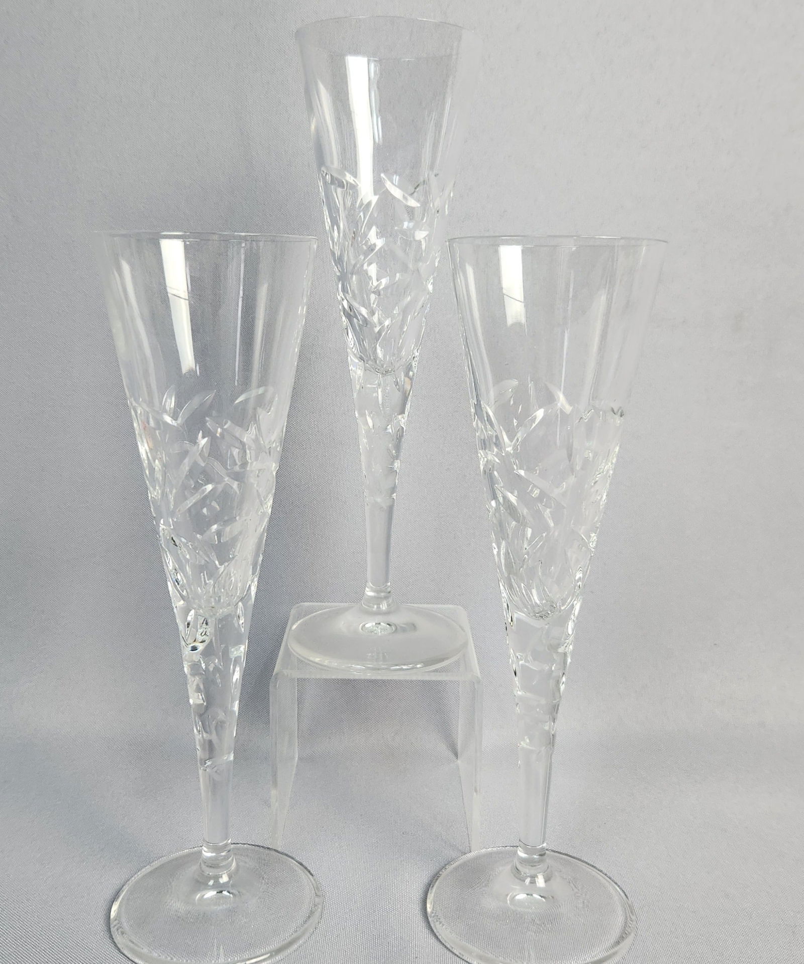 Three Royal Doulton Central Park Crystal Flutes: Three Royal Doulton Central Park crystal flutes. Each flute features a tall, slender bowl, long stem, and round foot. The upper portion of the stem and the lower half of the bowl are adorned with a tr