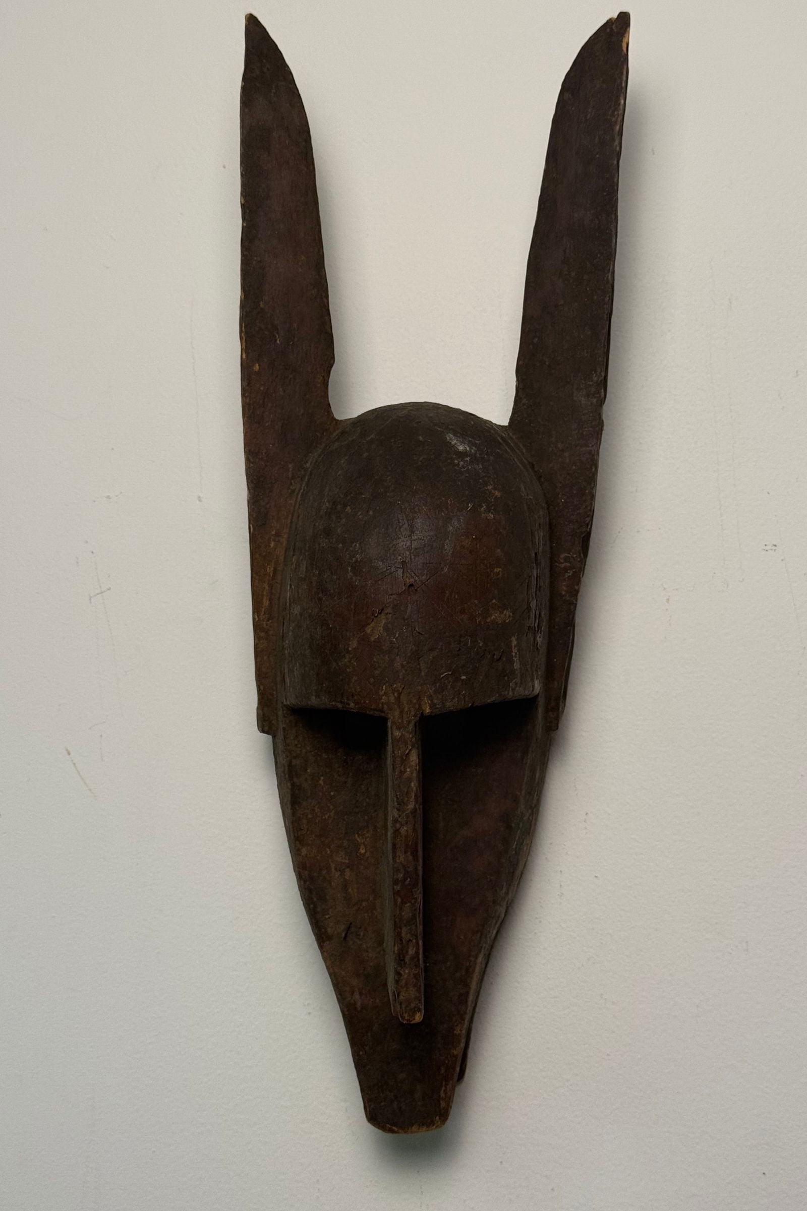 Bambara (Bamana) Hyena (Suruku) Mask, Mali: A Bambara (Bamana) Hyena (Suruku) Mask from Mali, Western Africa. This carved wooden mask features an elongated and stylized form, characterized by a prominent, ridge-like nose, deeply recessed eye ar