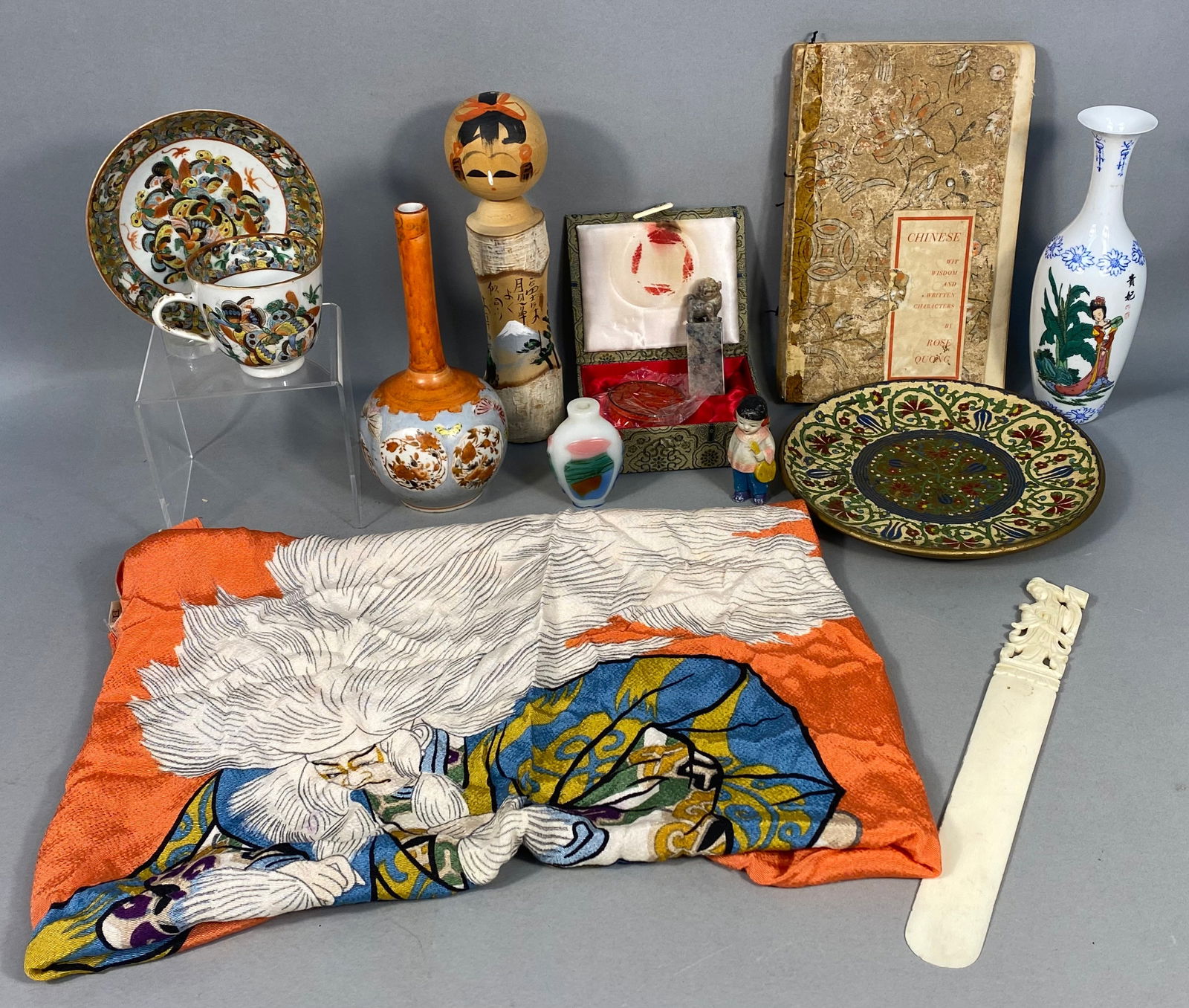 A Collection of East Asian Decorative Arts, including a Japanese Kabuki Kagami Jishi Rayon Furoshiki: A diverse collection of East Asian decorative arts. The primary item is a scarf or textile panel of rayon, tagged "?????®" (Fujimiyabi®) and "???? 100%" (Rayon 100%), depic