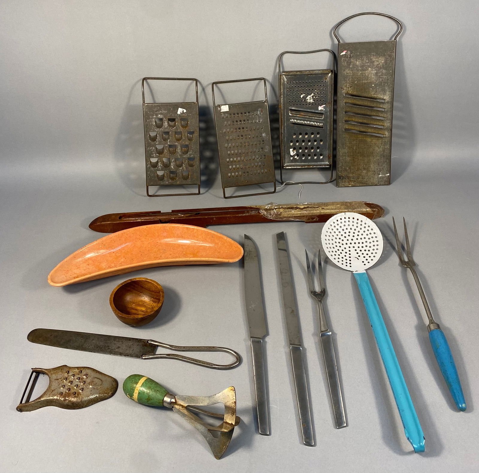 A Collection of Vintage Kitchen Utensils and Gadgets: A collection of vintage kitchen utensils and gadgets, predominantly metal with some wooden and plastic components. The lot includes four tin-plated steel slicers/graters, one marked "MFD BY BLUFF