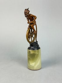 A Patinated Bronze Figural Sculpture of a Satyr on a Unicycle, Mounted on Onyx