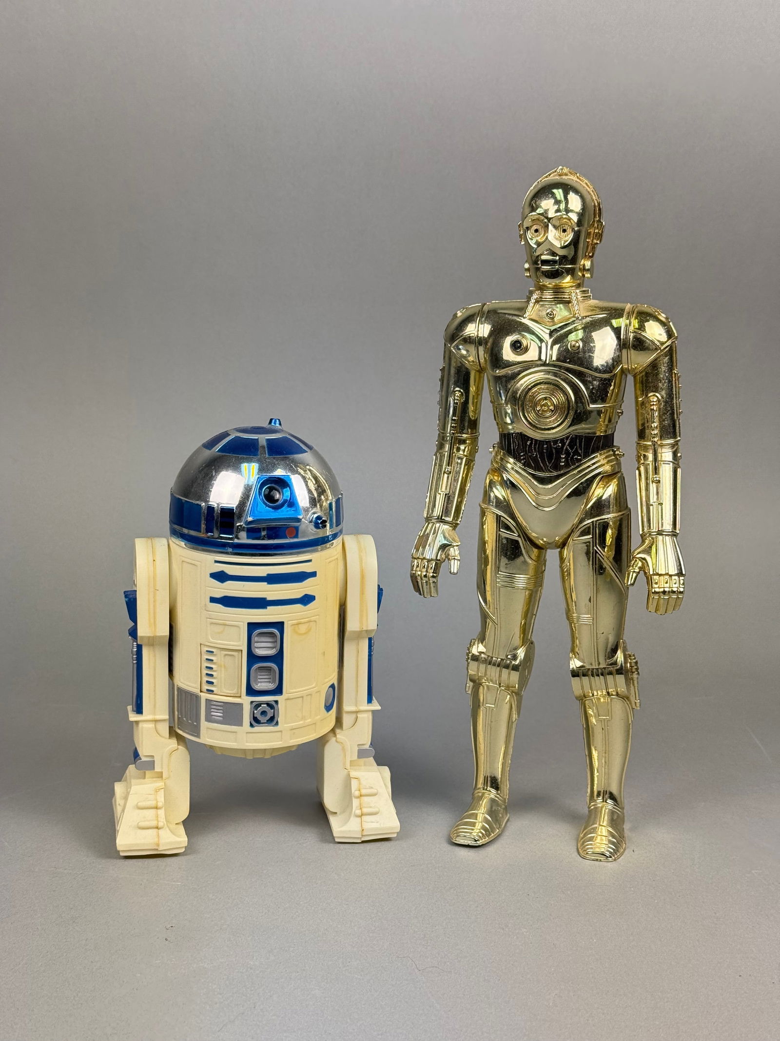Kenner Star Wars C-3PO and R2-D2 12 Inch Action Figures: A pair of vintage Kenner Star Wars action figures, comprising C-3PO and R2-D2, both dated 1978. The taller figure, C-3PO, is a humanoid form rendered in metallic gold-finished plastic, featuring artic
