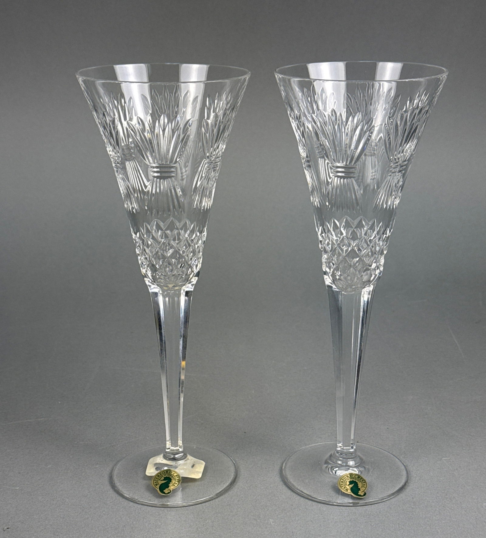 A Pair of Waterford Crystal Millennium Prosperity Toasting Flutes: A pair of Waterford Crystal Millennium Prosperity toasting flutes. Each clear cut crystal flute features a tapered bowl with intricate decorative cutting, including a repeating diamond pattern at the