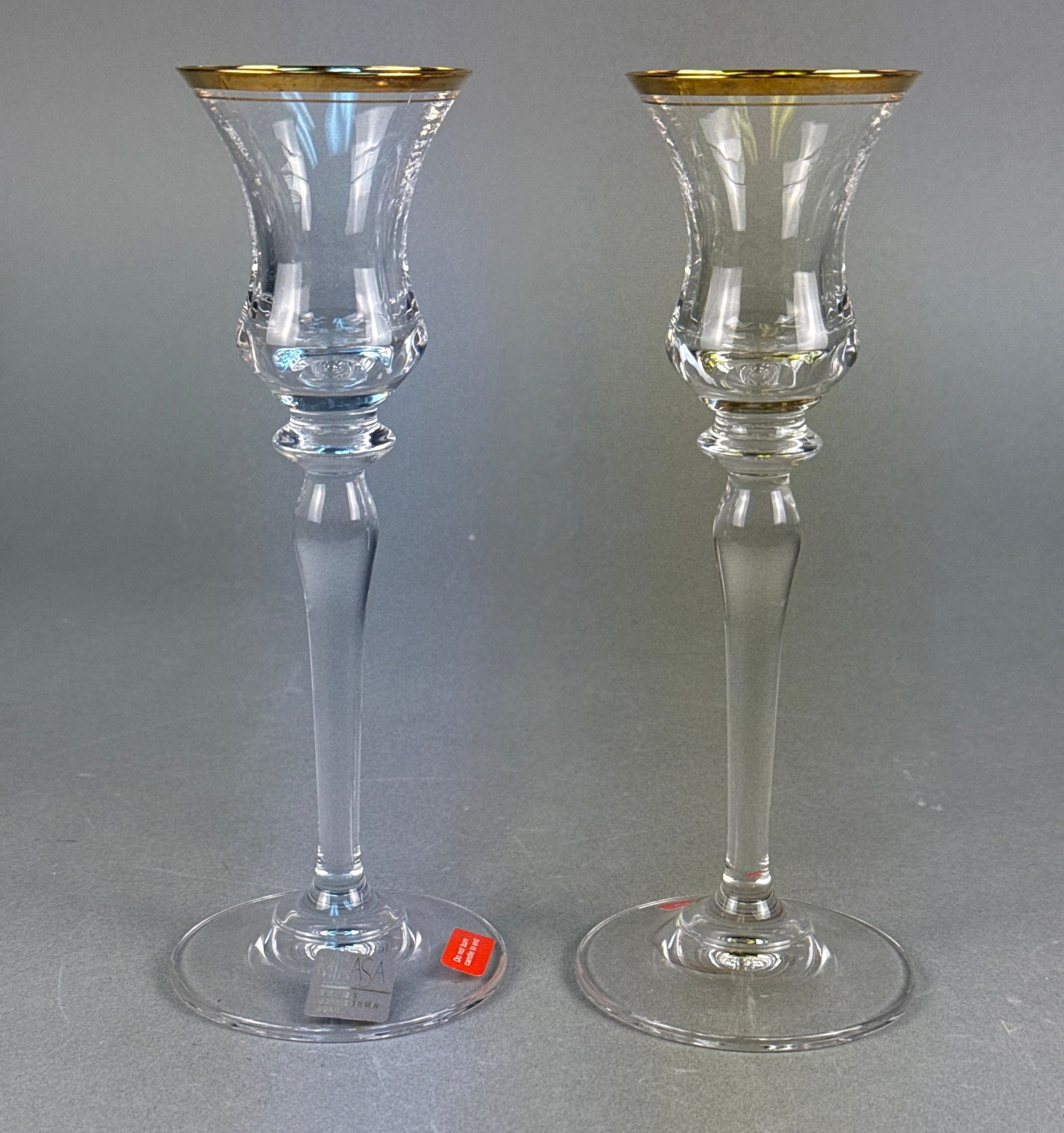 A Pair of MIKASA Jamestown Gold Crystal Candlesticks: A pair of MIKASA 'Jamestown Gold' crystal candlesticks. Each features a slender stem, a wide circular foot, and a trumpet-shaped bowl adorned with an etched or cut pattern and a gold-colored band alon