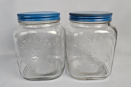 A Pair of Monarch Finer Foods Lion's Head Glass Lidded Jars