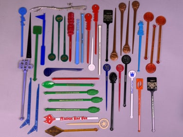 A Collection of Vintage Promotional Cocktail Stirrers and a Metal Tong