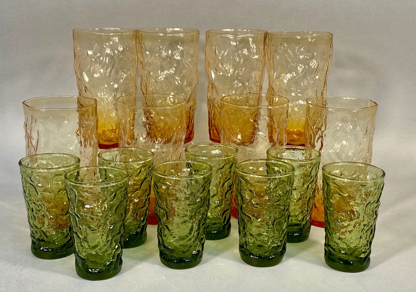 A Collection of Sixteen 'Crinkle' Pattern Amber and Olive Green Drinking Glasses: A collection of sixteen drinking glasses in the 'Crinkle' pattern, widely attributed to either Libbey or Anchor Hocking, dating from the mid-20th century. The collection comprises eight glasses in an