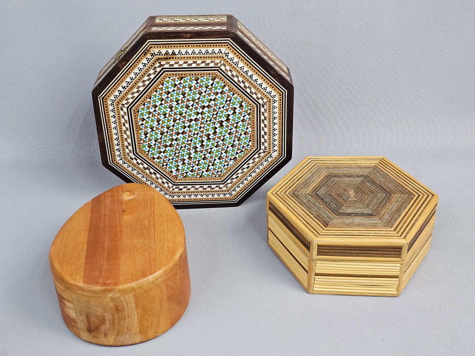 A Group of Three Decorative Boxes, including an Egyptian Wooden Mother of Pearl Inlaid Octagonal: Octagonal box: 7.5 inches wide Hexagonal box: 6 inches wide Oval box: 5 inches long The octagonal inlaid box is in generally good condition with minor surface wear consistent with age and use. Some w