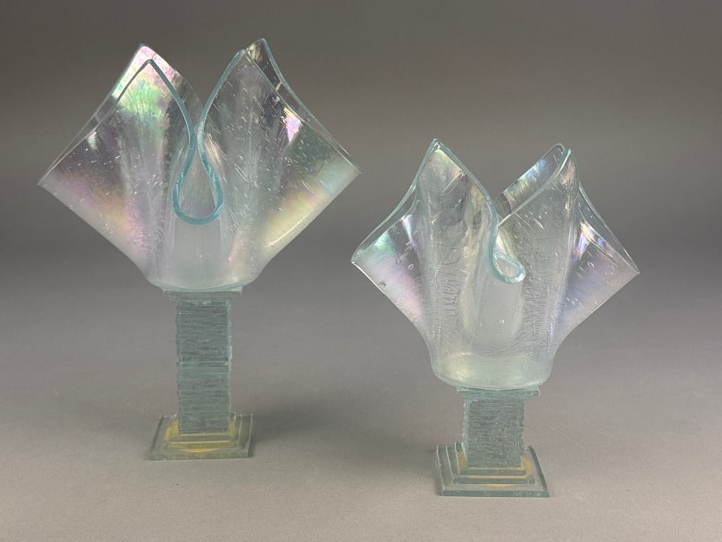 A Pair of Isis Glass Iridescent Handkerchief Candl: A pair of Isis Glass iridescent handkerchief candle vases, copyrighted 1987. Each piece is crafted from clear glass, featuring a textured, stepped square base that supports an upward-flaring, four-lob