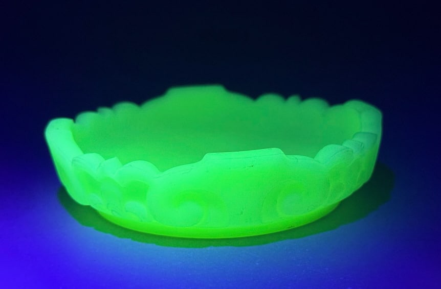 Fenton Uranium Custard Satin Glass Water Lily Bowl: A Fenton Uranium Custard Satin Glass Water Lily Bowl. This small, round, decorative dish or shallow bowl is made of molded glass, exhibiting strong green luminescence under ultraviolet light, indicati