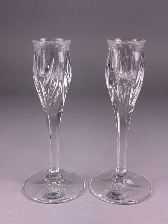 A Pair of Gorham 'Star Blossom' Full Lead Crystal: A pair of Gorham 'Star Blossom' full lead crystal candlesticks. Each candlestick features a modern aesthetic with intricate swirling cut patterns on its upper body, smooth stem, and plain round base.