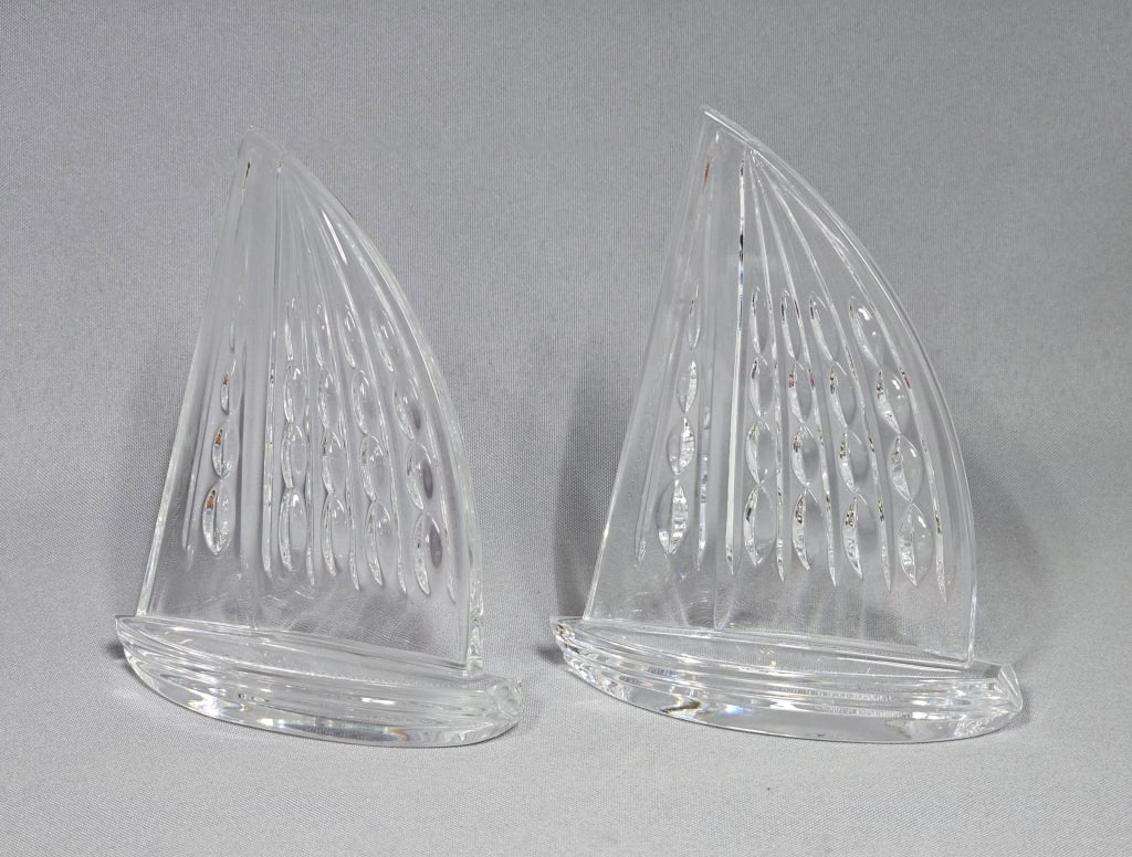 A Pair of Waterford Crystal Sailboat Paperweights: A pair of Waterford Crystal sailboat paperweights, each crafted from clear cut crystal. The design features an abstract upward-curving sail with vertical fluting and multiple rows of oval-shaped cuts,