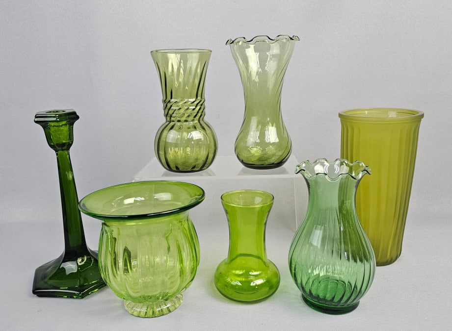 Seven Mid-Century Green Glass Vases and a Candlest: This lot comprises seven pieces of green glass, consisting of six vases and one candlestick. The items exhibit a range of green hues, from translucent deep emerald and chartreuse to a more opaque, fro