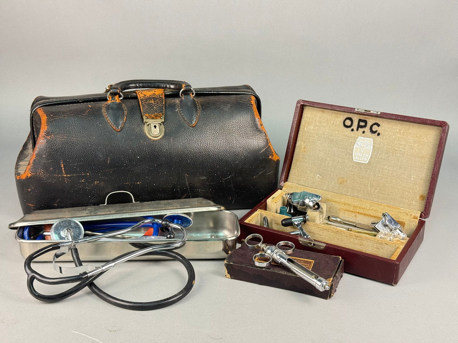 Vintage Schell Cowhide Leather Doctor's Bag and Collection of 23 Medical Instruments: A collection of 23 vintage medical instruments and containers centered around a black leather frame-style doctor's bag attributed to Schell Cowhide Leather, consistent with early-to-mid 20th-century p