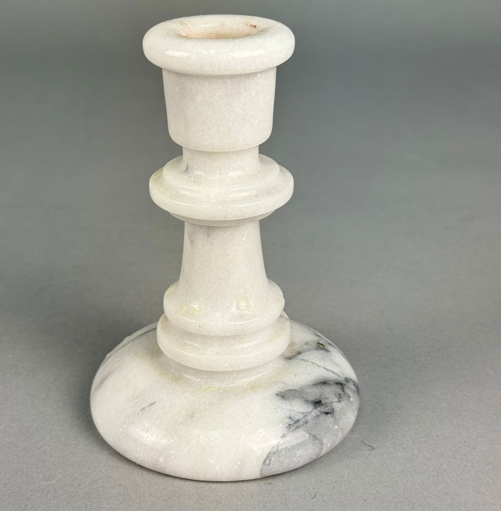 A Vermont Marble Baluster-Form Candlestick: A single baluster-form candlestick crafted from polished white marble. The object features a classic turned design typical of 20th-century decorative pieces, rising from a wide, circular base. The mar