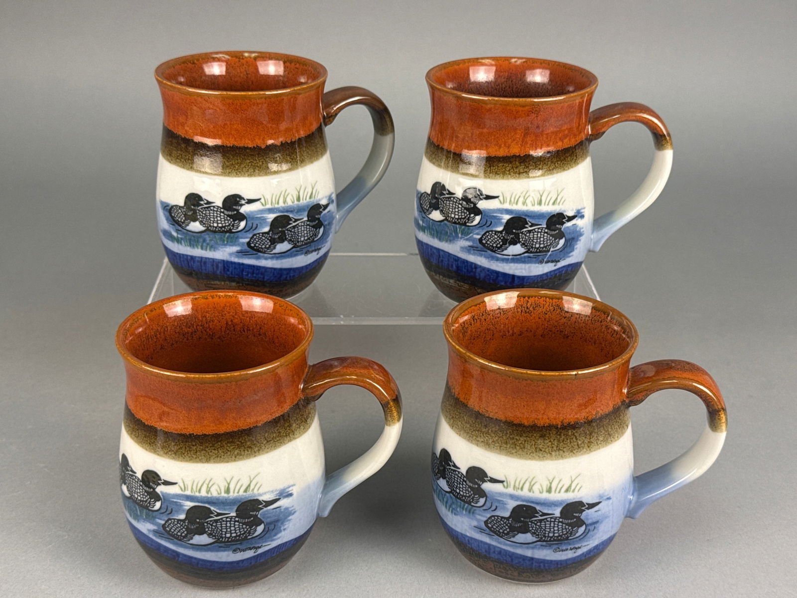 A Collection of 4 Late 20th Century Stoneware Mugs with Loon Transfer Print: A collection of four matching ceramic stoneware mugs, consistent with late 20th-century studio pottery or mass-produced stoneware aesthetics. Each mug features a rounded body and a robust, horizontall
