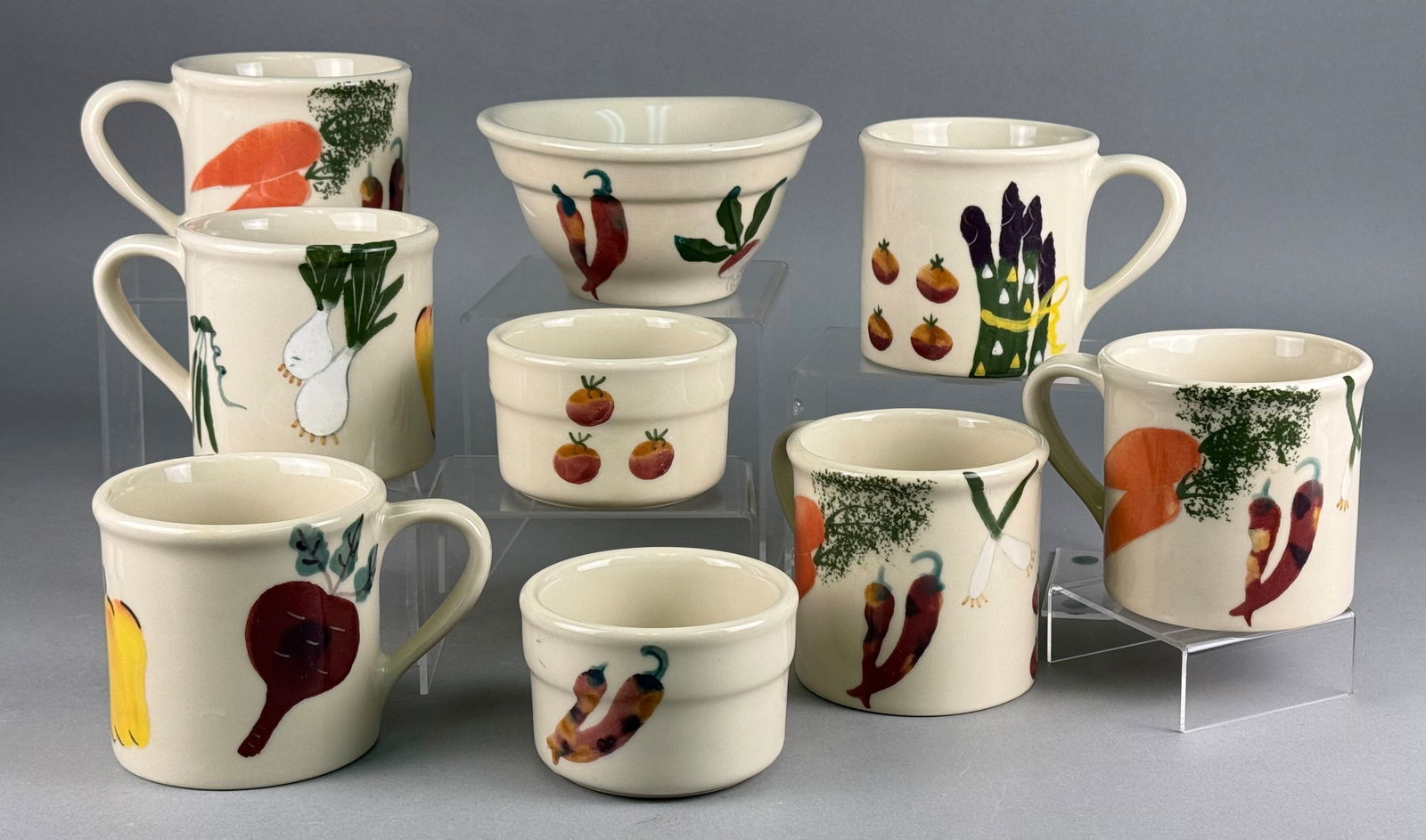 A Collection of Nine Hartstone Pottery Stoneware Pieces with Hand-Painted Vegetable Motifs: A collection of nine pieces of contemporary stoneware ceramic ware manufactured by Hartstone Pottery of Zanesville, Ohio. The grouping consists of six handled mugs, two small handleless cups or rameki