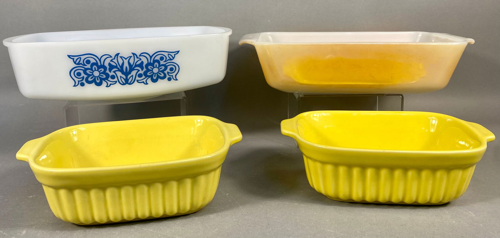 A Collection of Four Vintage Ovenware Dishes, including Pfaltzgraff FTDA 1983 and Anchor Hocking: The lot comprises four pieces of vintage ovenware, consisting of two ceramic dishes and two opalescent glass baking dishes. The collection includes a pair of identical bright yellow ceramic (likely st