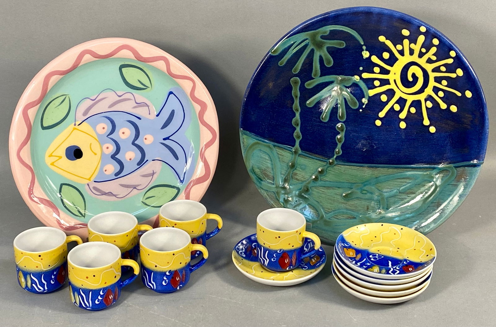 A Collection of Earthworks Barbados Hand-Painted Ceramic Pieces: A collection of fourteen pieces of hand-painted glazed ceramic pottery attributed to Earthworks Barbados, featuring vibrant marine and tropical motifs. The collection comprises two large decorative pl