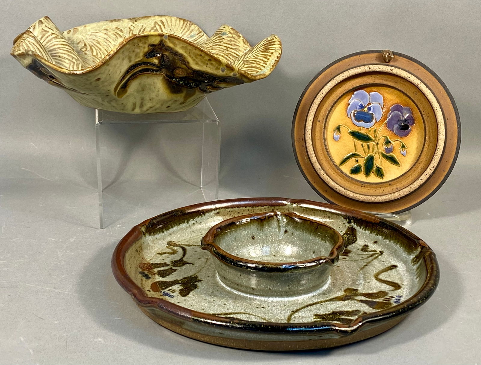 A Trio of Contemporary Studio Stoneware Pottery Pieces: A collection of three pieces of contemporary studio stoneware pottery, characterized by speckled clay bodies and earth-toned glazes. The first item is a large, irregularly shaped serving bowl or dish