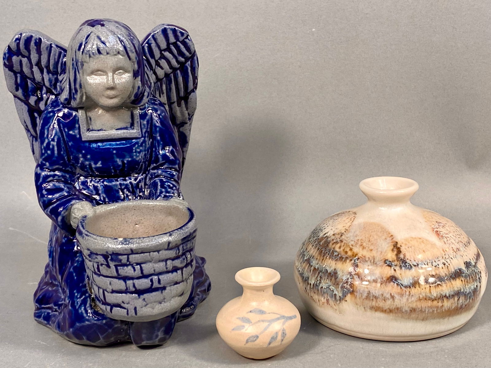 A Trio of Studio Pottery Pieces Including Rowe Pottery Works Salt Glazed Angel Votive and Kravec: A trio of American studio pottery pieces. The collection includes a Rowe Pottery Works salt-glazed stoneware figurine depicting a kneeling angel holding a textured basket vessel, executed in a glossy