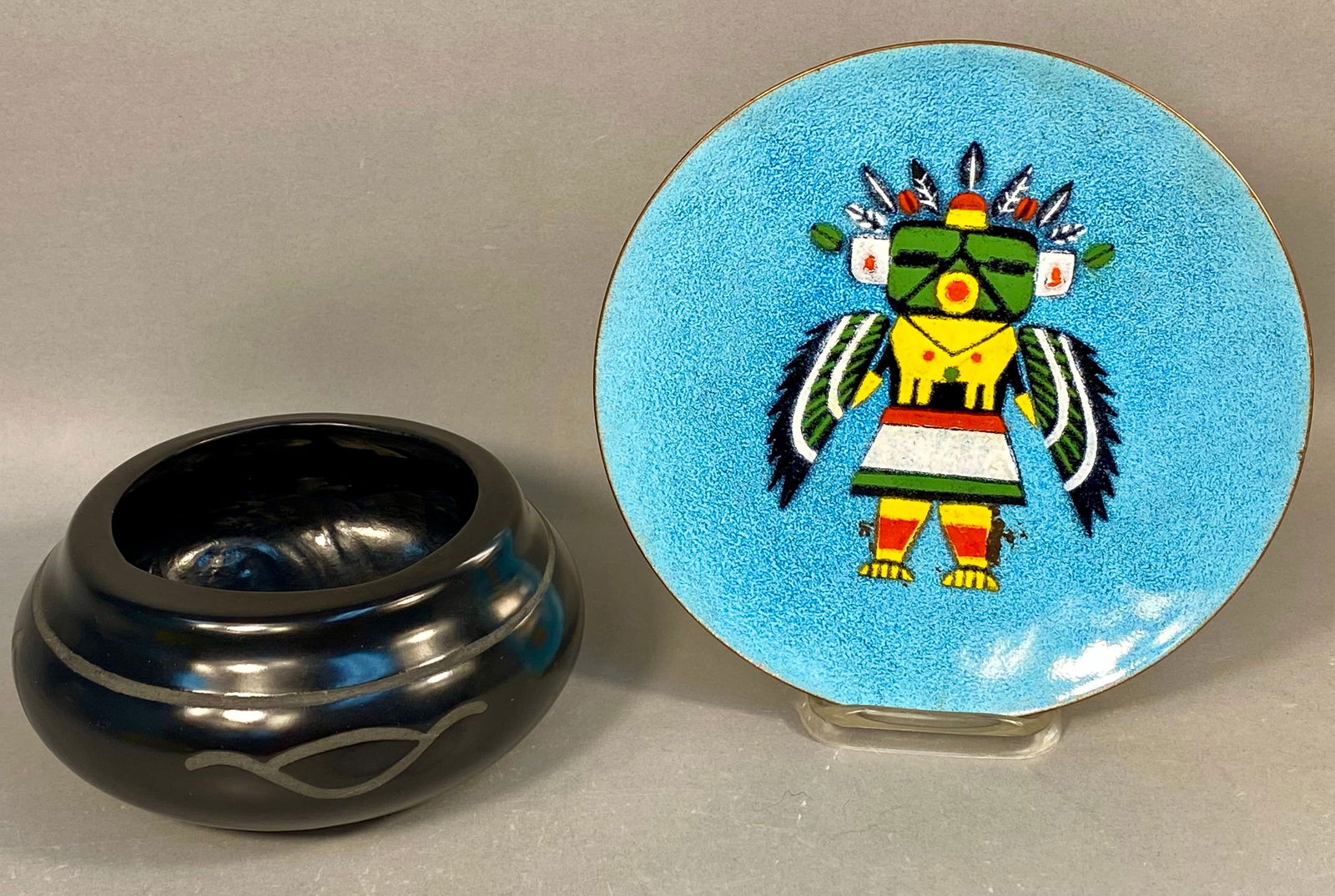Annemarie Davidson Kachina Enamel on Copper Plate and Blackware Pottery Vessel: This lot comprises two items: an enamel on copper plate by Annemarie Davidson and an accompanying blackware ceramic vessel. The circular enamel plate features a stylized Southwestern figure, identifie
