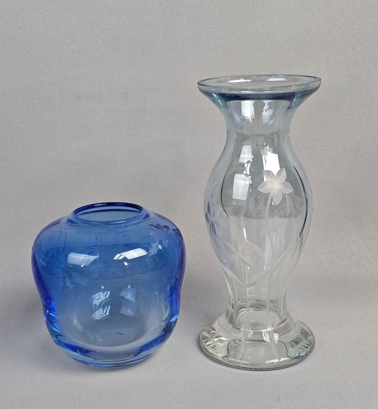 A Pair of Etched Glass Vases: A Lenox Handcut Crystal Petite Etched Floral Blue Vase and a Signed: A Lenox Handcut Crystal Petite Etched Floral Blue Vase, featuring a clear glass body with a subtle light blue hue, a flared rim, slender body, and pedestal foot. The vase is adorned with etched floral