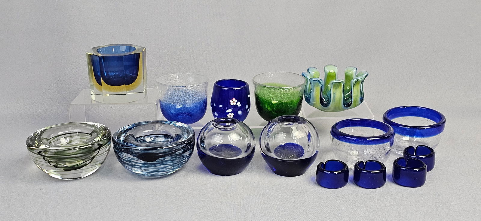 A Collection of Modern Art Glass Votives and Decorative Vessels, with a Set of Four Glass Rings: A collection of fifteen modern art glass objects, primarily comprising small decorative vessels suitable for votives or general display, along with a set of four complementary glass rings. The pieces
